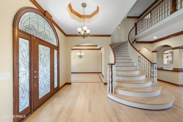 foyer entrance featuring crown molding, a notable chandelier, and light wood-type flooring