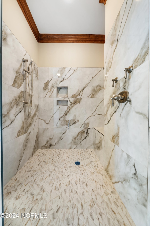 bathroom with a tile shower and ornamental molding