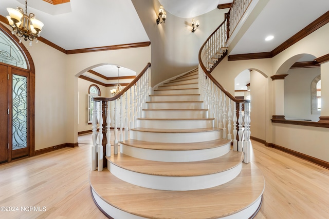 foyer featuring crown molding, a wealth of natural light, light wood-type flooring, and an inviting chandelier