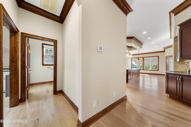 hall featuring light hardwood / wood-style floors, a notable chandelier, ornamental molding, and sink