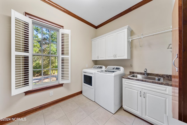 washroom featuring light tile patterned floors, sink, washer and clothes dryer, crown molding, and cabinets