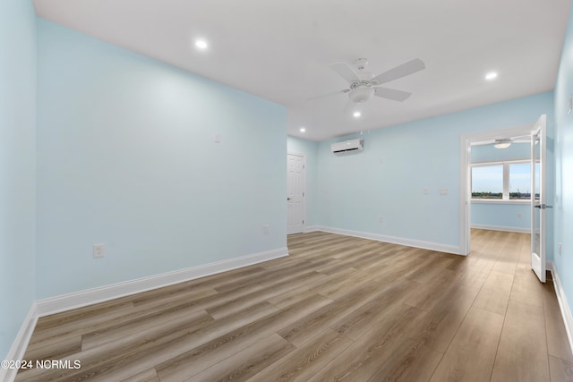 spare room with light hardwood / wood-style floors, a wall mounted air conditioner, and ceiling fan