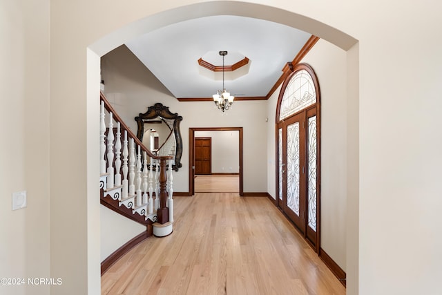 entryway featuring crown molding, a chandelier, and light wood-type flooring