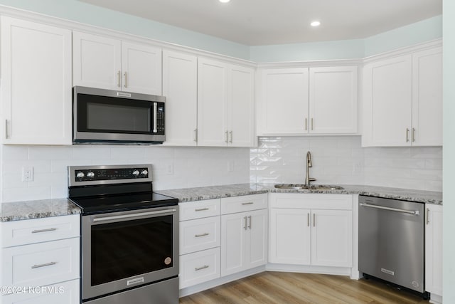 kitchen featuring tasteful backsplash, sink, light wood-type flooring, stainless steel appliances, and white cabinets