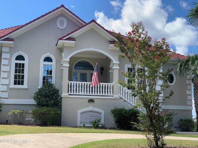 mediterranean / spanish house featuring a front lawn and a balcony