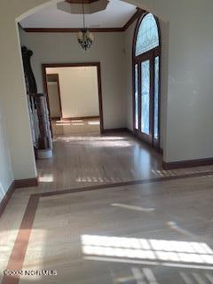 entrance foyer with an inviting chandelier, crown molding, and wood-type flooring