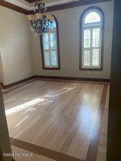 unfurnished dining area with ornamental molding, a chandelier, and wood-type flooring