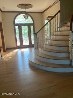 foyer featuring french doors, crown molding, an inviting chandelier, and hardwood / wood-style floors