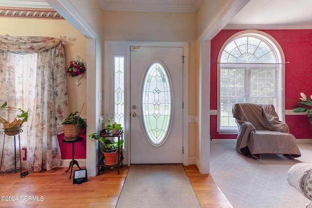 foyer entrance with light hardwood / wood-style floors and ornamental molding