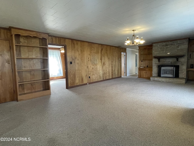 unfurnished living room with a stone fireplace, light colored carpet, and an inviting chandelier