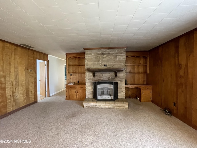 unfurnished living room with crown molding, light colored carpet, a fireplace, and wood walls