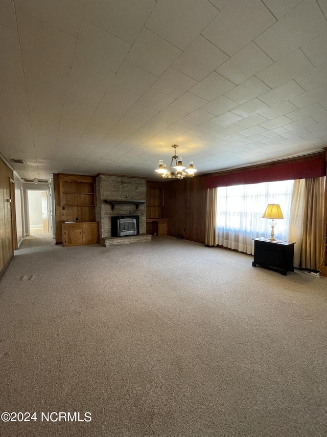 unfurnished living room with a stone fireplace, carpet floors, and a chandelier