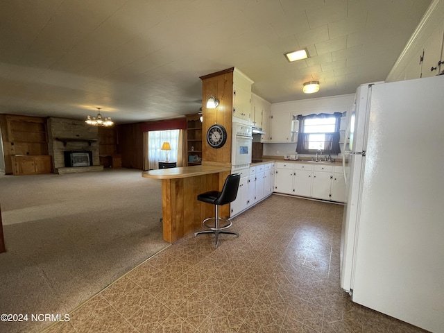 kitchen featuring white cabinetry, a breakfast bar area, carpet, kitchen peninsula, and white appliances