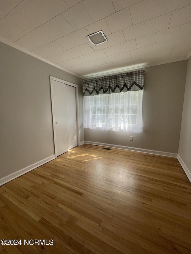 unfurnished room featuring wood-type flooring and ornamental molding