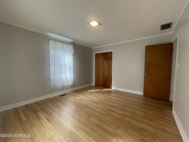 unfurnished bedroom featuring ornamental molding, a closet, and light wood-type flooring