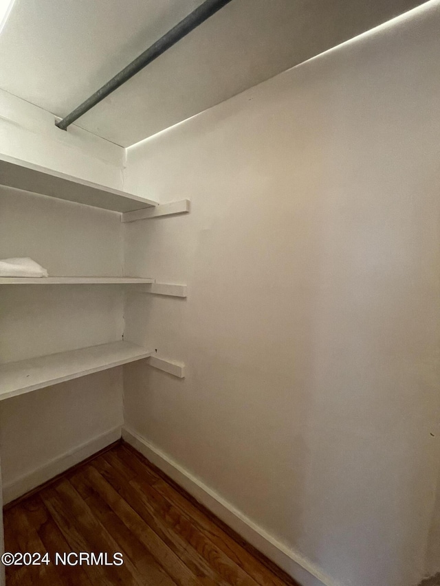 walk in closet featuring dark wood-type flooring and built in desk