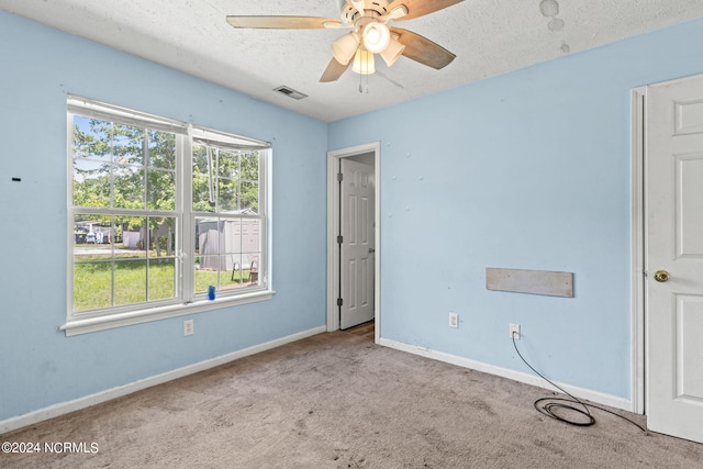 carpeted spare room with a textured ceiling and ceiling fan