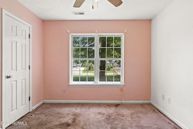 spare room featuring a textured ceiling, ceiling fan, and carpet