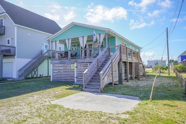 rear view of property with a porch, a yard, and a patio area