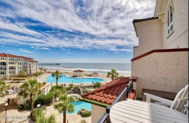 balcony with a water view and a community pool