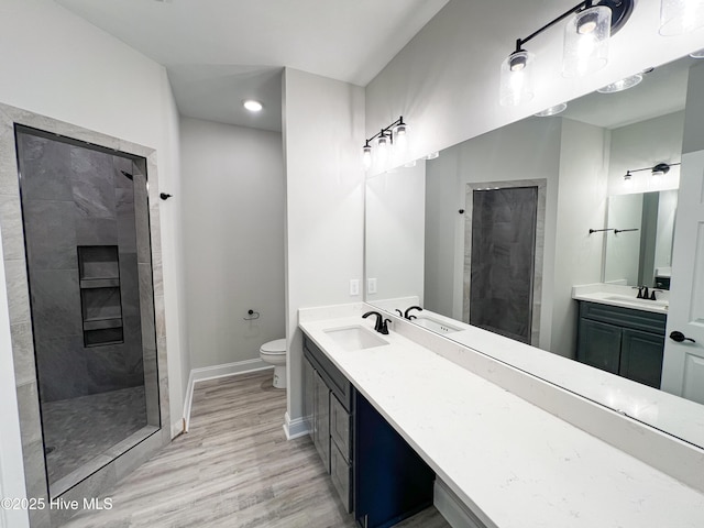 bathroom with tiled shower, vanity, hardwood / wood-style flooring, and toilet