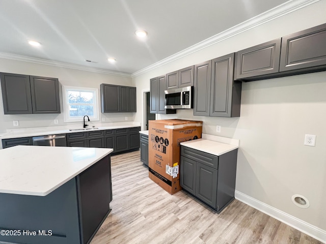 kitchen featuring appliances with stainless steel finishes, light hardwood / wood-style flooring, ornamental molding, and sink