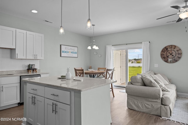 kitchen with ceiling fan with notable chandelier, a center island, dishwasher, pendant lighting, and hardwood / wood-style flooring