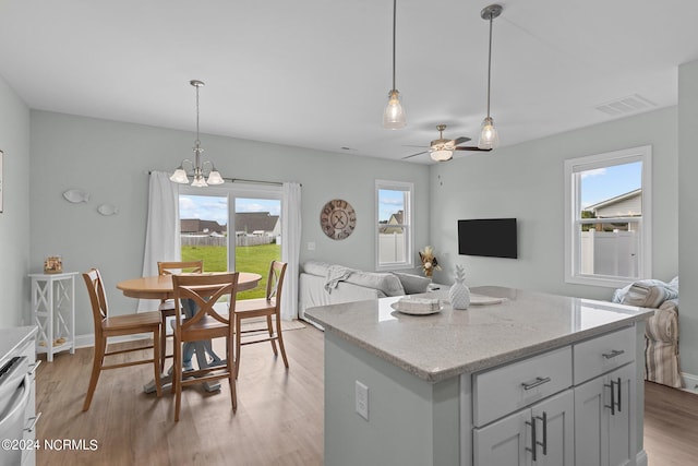 kitchen featuring wood-type flooring, a kitchen island, hanging light fixtures, and a wealth of natural light