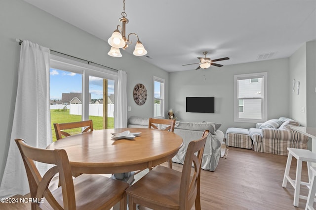 dining area with ceiling fan with notable chandelier and hardwood / wood-style flooring