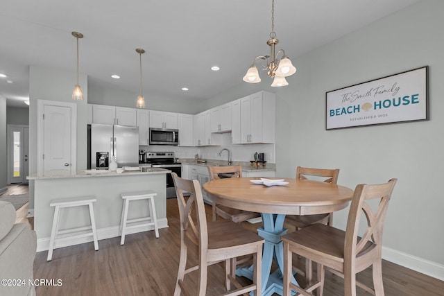 dining area featuring dark hardwood / wood-style floors, sink, and an inviting chandelier