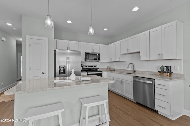 kitchen with a center island, wood-type flooring, stainless steel appliances, and decorative light fixtures