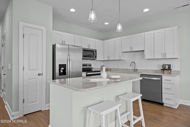 kitchen with decorative light fixtures, a center island, hardwood / wood-style floors, and stainless steel appliances