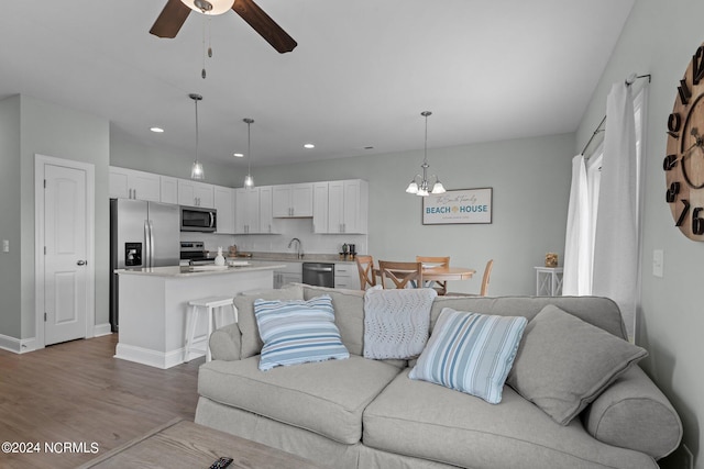 living room with ceiling fan with notable chandelier and wood-type flooring