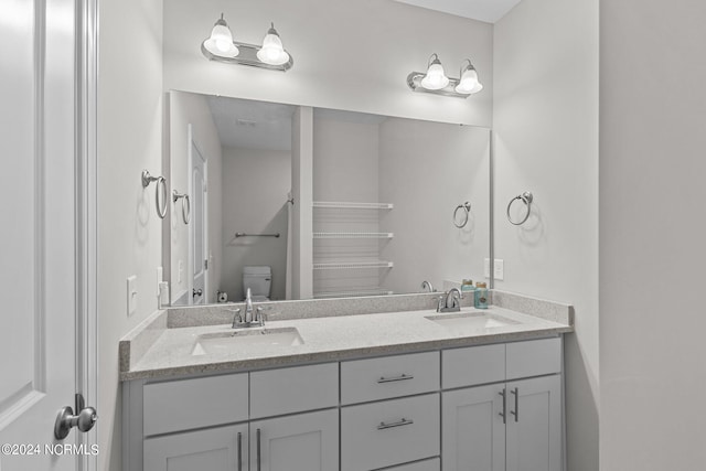 bathroom with double vanity and toilet