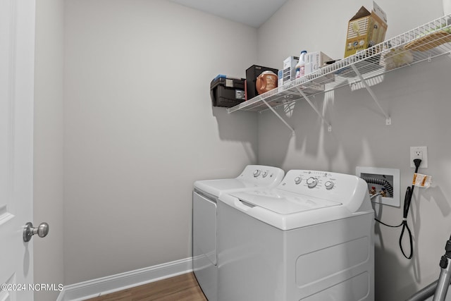 clothes washing area with washing machine and dryer and hardwood / wood-style flooring