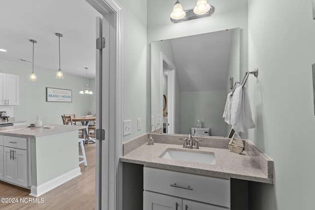 bathroom featuring a chandelier, lofted ceiling, hardwood / wood-style floors, and double sink vanity