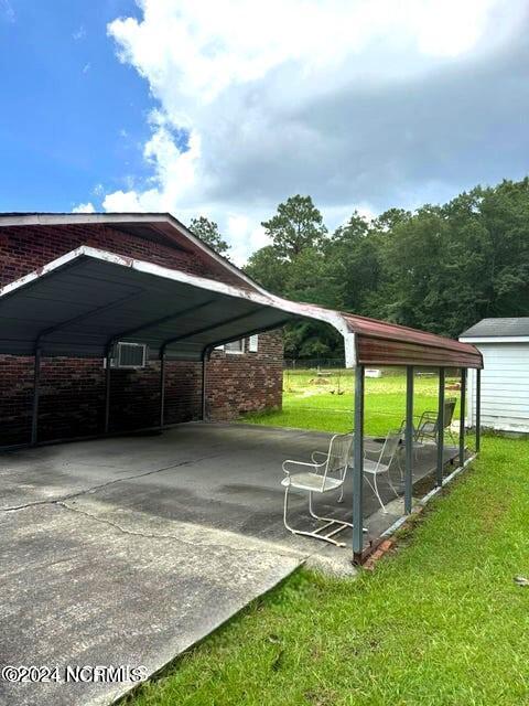 view of parking / parking lot with a carport and a lawn