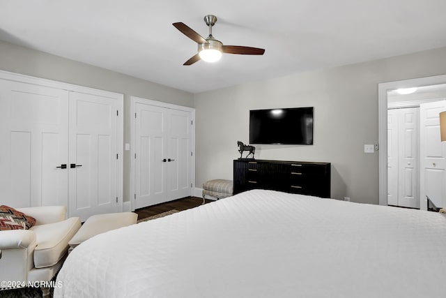 bedroom with a ceiling fan, dark wood finished floors, baseboards, and two closets