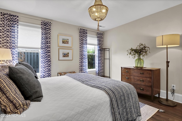 bedroom featuring an inviting chandelier, wood finished floors, visible vents, and baseboards