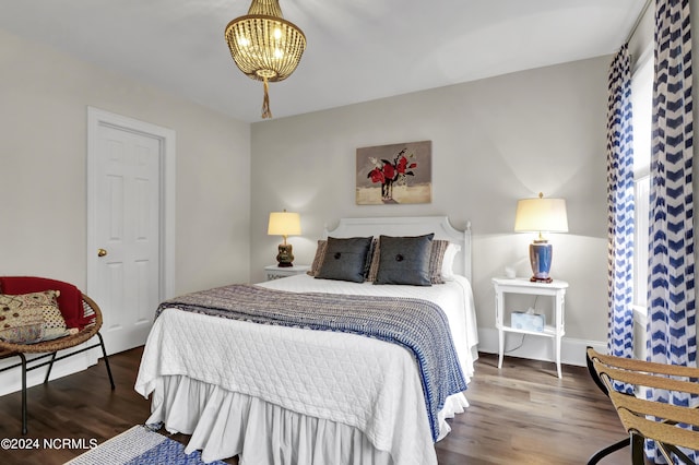 bedroom with wood finished floors and an inviting chandelier