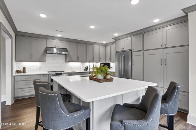 kitchen with dark wood-type flooring, gray cabinets, high end appliances, and a kitchen island