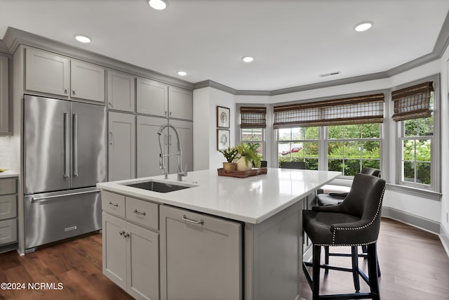 kitchen with dark wood-style flooring, high end fridge, light countertops, gray cabinetry, and a sink