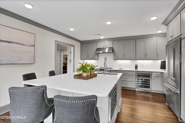 kitchen featuring beverage cooler, high end fridge, gray cabinets, and under cabinet range hood