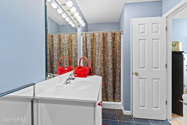 bathroom featuring tile patterned floors, vanity, a textured ceiling, and toilet