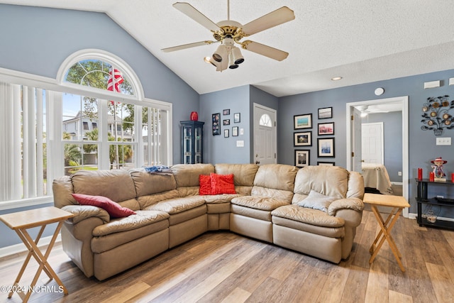 living room featuring light hardwood / wood-style flooring, a textured ceiling, ceiling fan, and high vaulted ceiling