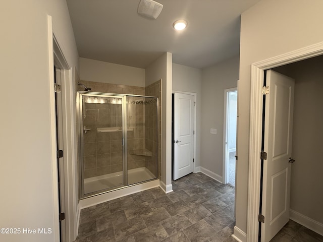 bathroom featuring stone finish floor, visible vents, a shower stall, and baseboards