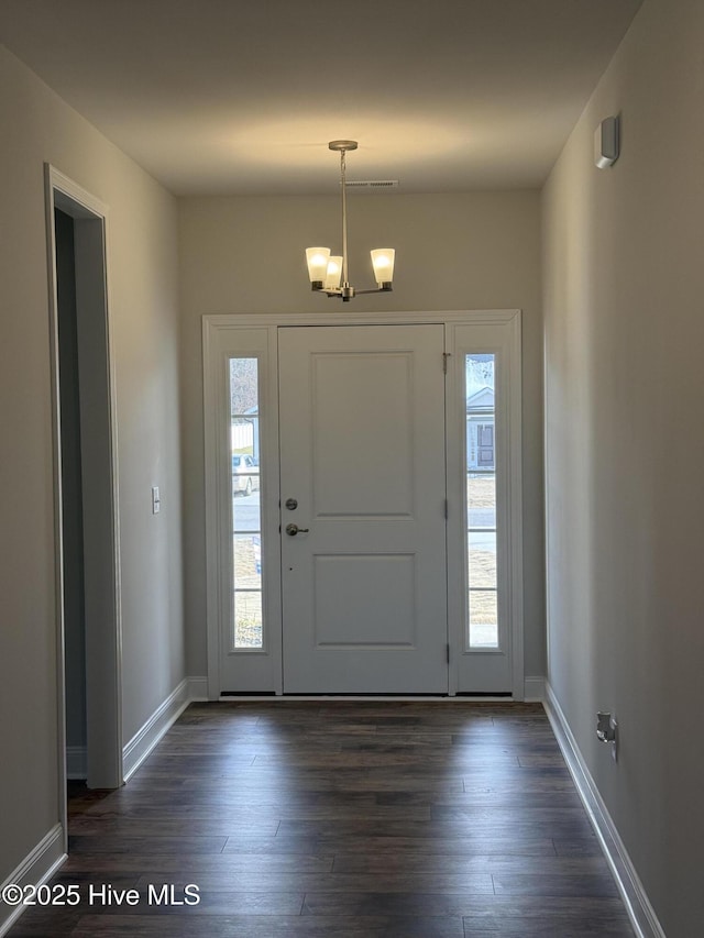 entryway featuring a healthy amount of sunlight, an inviting chandelier, and dark wood finished floors