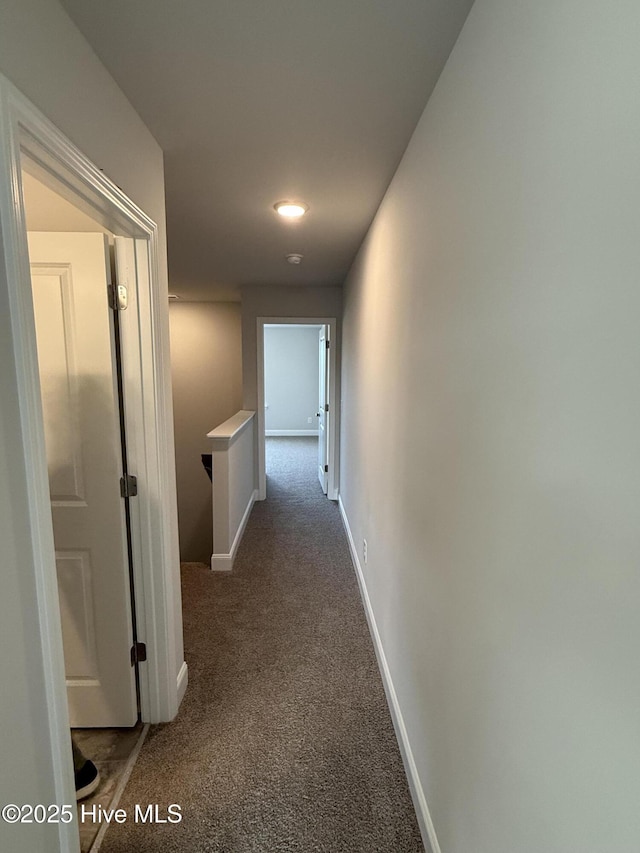 hall featuring carpet floors, an upstairs landing, and baseboards