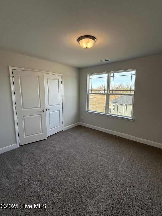 unfurnished bedroom featuring dark colored carpet, visible vents, and baseboards