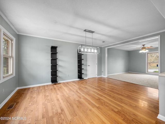 unfurnished room with crown molding, ceiling fan with notable chandelier, light hardwood / wood-style flooring, and a textured ceiling